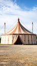 Classic striped circus big top tent standing in an open field under a blue sky. Royalty Free Stock Photo