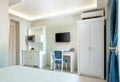 Classic style white and blue interior of hotel room with kitchen module cupboard cabinet, wardrobe and TV table in single space