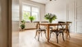 Classic styled wooden dining table with chairs decorated with vase with fresh flowers in spacious light room with white walls and