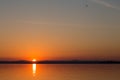 Classic sunset on a lake, with sun low on the horizon and flying Royalty Free Stock Photo