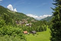 Classic swiss chalet in the middle of green alpine meadows . Cozy rural village Champery in Switzerland. Bright blue sky and white Royalty Free Stock Photo