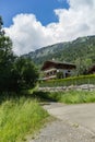 Classic swiss chalets along rustic local road. Cozy rural village Champery in Switzerland. Bright blue sky and white fluffy clouds Royalty Free Stock Photo