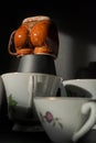 Classic tea cups around a provocative woman-shaped cup
