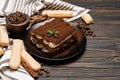 Classic tiramisu dessert on ceramic plate and savoiardi cookies on wooden background
