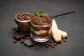 Classic tiramisu dessert in a glass cup and pieces of chocolate on dark concrete background Royalty Free Stock Photo