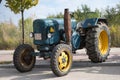 classic tractor, it is a green tractor with yellow wheels parked in the street