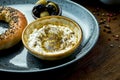 Classic Turkish breakfast - simit with feta cheese mousse with olive oil and spices, served on blue plate with olives. Wood