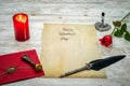 Classic Valentine`s Day cad with decorative quill and stand, red envelop with wax seal, red candle and rose, space for your text Royalty Free Stock Photo