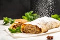 Classic Viennese Christmas strudel with apples, mint and raisins, with star anise, cinnamon sticks, sieve sprinkling sugar powder