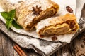 Classic Viennese Christmas strudel with apples, mint and raisins. on a wooden cutting board with star anise, cinnamon sticks, top