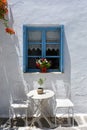 Classic view of a Greek blue window with coffee table and chairs on the Cyclades island