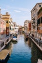 Classic view of the narrow sea Venetian canal. Colorful buildings stand opposite each other, boats moored near shore