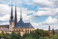 Classic view of the Notre-Dame Cathedral in Luxembourg with high spires and the flag of the country