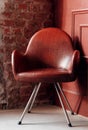 Classic vintage armchair with torn leather upholstery in grunge room with red brick and wooden wall. Royalty Free Stock Photo