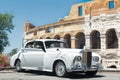 Classic vintage white wedding car at famous Colosseum or Coliseum building wall background Royalty Free Stock Photo