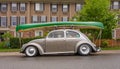 Classic Volkswagen Beetle with boat load up on top parked in a street. Ready for travel