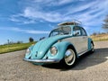 Classic VW beetle car against blue sky with wispy clouds Royalty Free Stock Photo