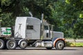 Classic white big rig semi truck tractor with loaded flat bed semi trailer standing on the rest area parking lot parallel to the Royalty Free Stock Photo