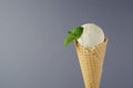 Classic white creamy ice cream in crisp waffle cone decorated green mint leaf on grey background, closeup, details, top. Royalty Free Stock Photo
