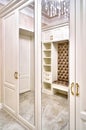 Classic white wardrobe with mirror doors in contemporary bright hallway. Carriage coupler closet bench