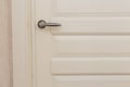 Classic white wooden milled door with chrome handle. White Scandinavian interior Royalty Free Stock Photo