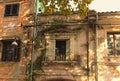 Classic wide-angle view of the facade of the abandoned building. Old windows with the wooden shutters. Weeds growing on the wall.