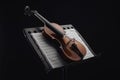 Classic wooden cello on opened music book on stand isolated on black.