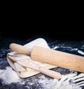 Classic wooden rolling pin with freshly prepared dough and dusting of flour on black background Royalty Free Stock Photo