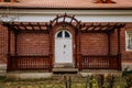 Classic wooden white carved oval door with glass inserts, brown canopy and lamp over porch, red block brick wall, entrance to Royalty Free Stock Photo