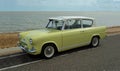 Classic Yellow Ford Anglia motor car on seafront promenade be Royalty Free Stock Photo