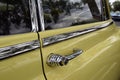 A classic Yellow Oldsmobile close up on chrome detailed door handle