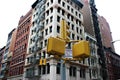 Classic yellow traffic lights at intersections in Manhattan against the background of buildings with fire escapes.