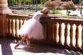 Classical ballet dancer dressed in a white tutu leaning on the railing of a park doing a beautiful ballet pose. Classical ballet Royalty Free Stock Photo