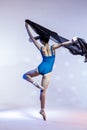 Classical Ballet Ideas. Young Japanese Female Ballet Dancer Dancing With Flying Black Cloth While Posing in Blue Bodysuit Against
