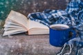 Classical blue colored cup of coffee with a knitted scarf and opened book on a wooden background Royalty Free Stock Photo