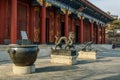 Classical Chinese sculptures stand in front of a colorful old building