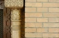 Classical design details: wooden column with antique oriental ornament and dark brick wall from outside.