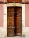 Classical double door made of warm red wood in Jaca, Huesca, Spain. Vintage entrance, classy antique details, floral curvy