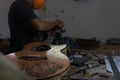 A classical guitar craftsman is pairing guitar strings to his guitar. He also adjusted the guitar tone at the guitar workshop