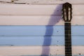 Classical guitar neck against pastel pink and blue beach hut