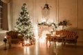 Classical interior of a white room with a decorated fireplace, sofa, Christmas tree, garlands, candles,lanterns, gifts Royalty Free Stock Photo