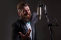 Classical music. Singing man in a recording studio. Expressive bearded man with microphone. Karaoke signer, musical Royalty Free Stock Photo