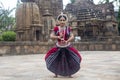 Classical Odissi Dancer wears traditional costume striking pose against the backdrop of Mukteshvara Temple, Bhubaneswar