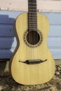 Classical parlour guitar resting against blue and pink beach hut