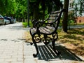 Classical shape old wooden and cast iron park bench along concrete sidewalk Royalty Free Stock Photo