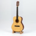 Classical six-stringed guitar gracefully standing on a wooden stand, capturing its inherent elegance on white background Royalty Free Stock Photo