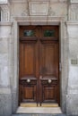 Dark wood double door entrance of old building in Paris France. Antique wooden doorway with golden metal doorknobs and stone wall. Royalty Free Stock Photo