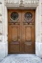 Double door entrance of historic building in Paris France. Vintage wooden doorway and stone fretwork decorations of stone wall. Royalty Free Stock Photo