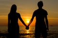 Couple silhouette holding hands at sunset by the sea Royalty Free Stock Photo
