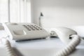 Classical white landline telephone with receiver off the hook